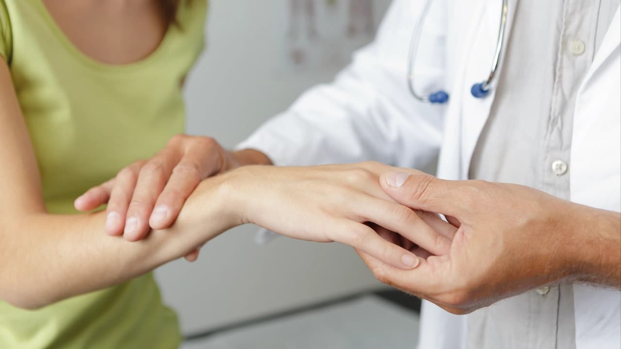 Doctor checking a hand showing carpal tunnel syndrome